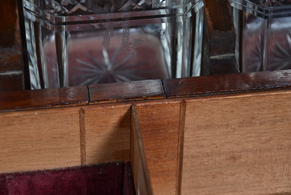 An Edwardian polished mahogany tantalus and games compendium featuring three cut crystal decanters and silver-toned brass strapwork mounts. View X