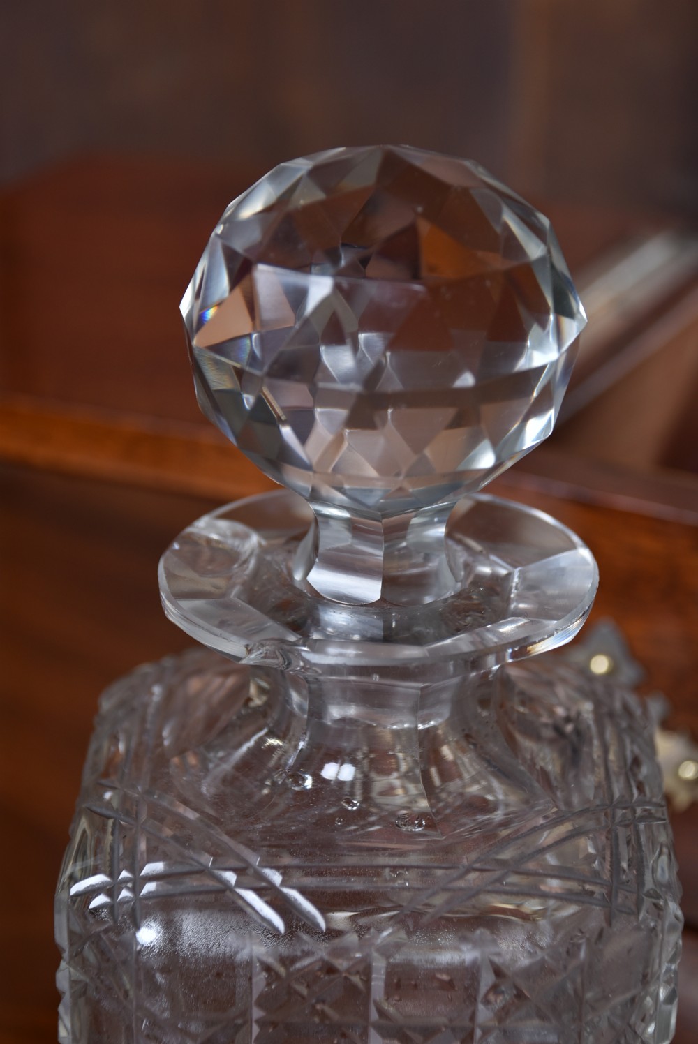 An Edwardian polished mahogany tantalus and games compendium featuring three cut crystal decanters and silver-toned brass strapwork mounts. View XV