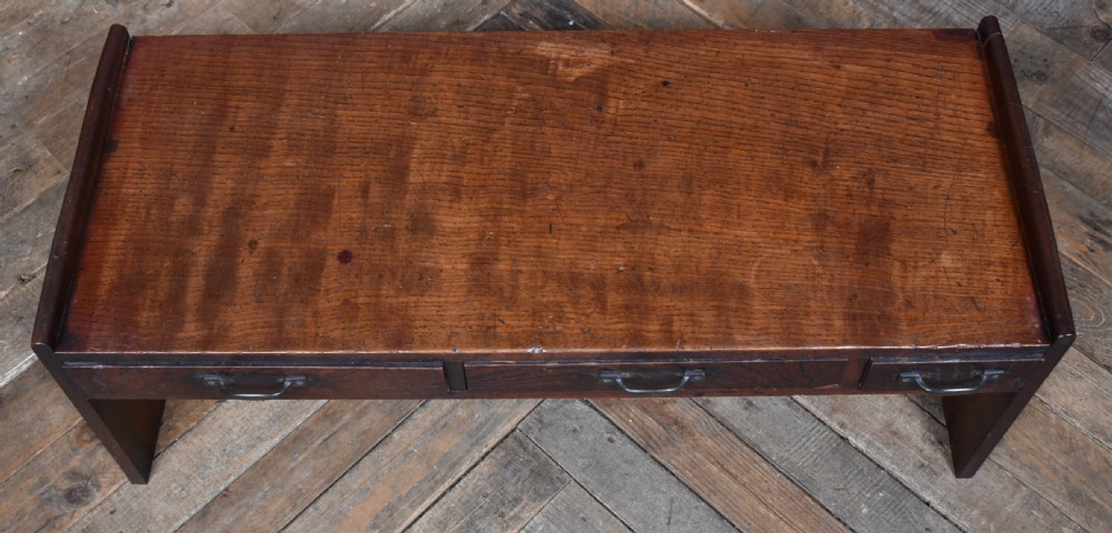 A low dark brown wooden Japanese calligraphy writing table featuring three drawers with iron handles and solid slab side supports. View III