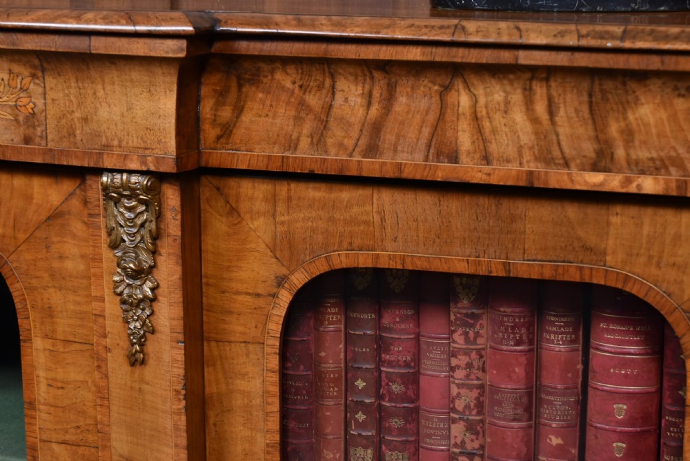 A low Victorian burr walnut breakfront bookcase featuring three arched glass doors, floral marquetry inlay, and gilt bronze mounts. View V