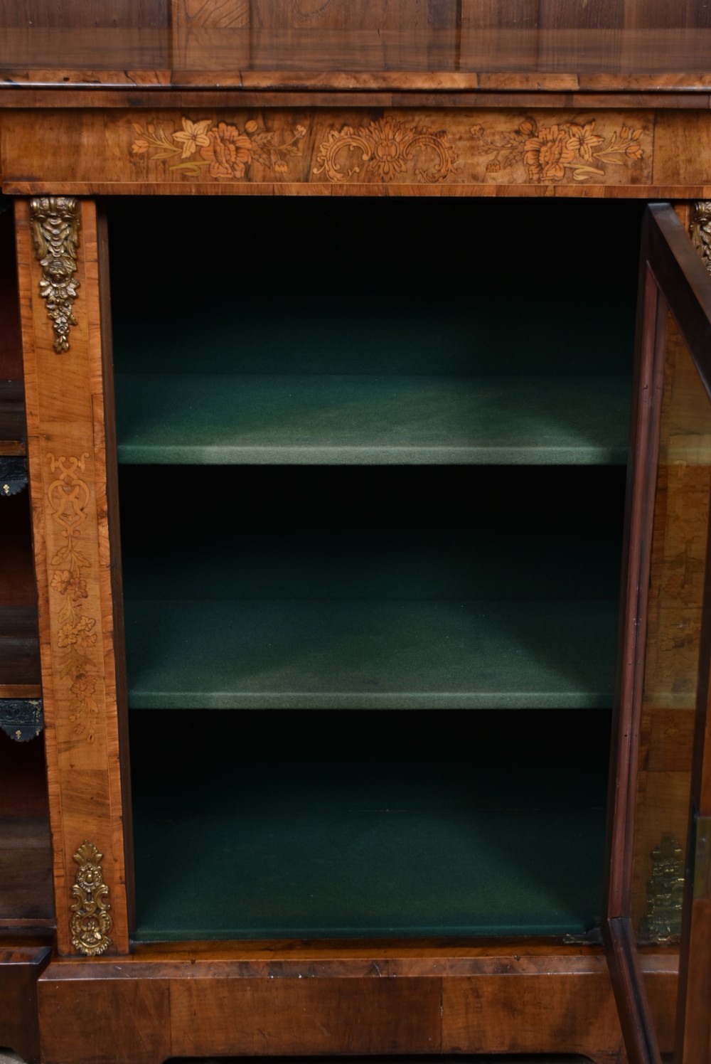 A low Victorian burr walnut breakfront bookcase featuring three arched glass doors, floral marquetry inlay, and gilt bronze mounts. View XII
