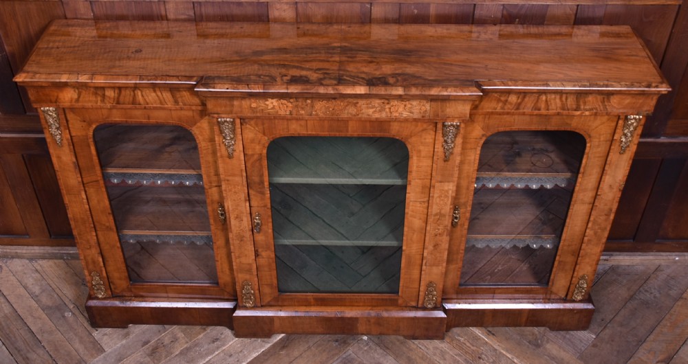 A low Victorian burr walnut breakfront bookcase featuring three arched glass doors, floral marquetry inlay, and gilt bronze mounts. View XV