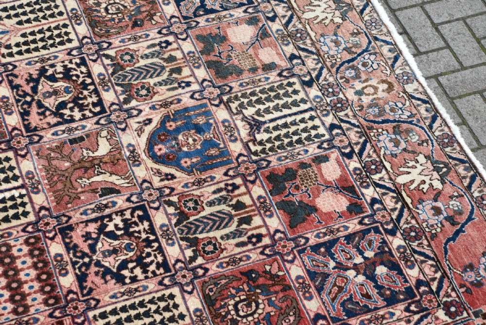 A hand-knotted Persian wool rug featuring a grid panel design with tree and floral motifs enclosed by a detailed terracotta border. View III