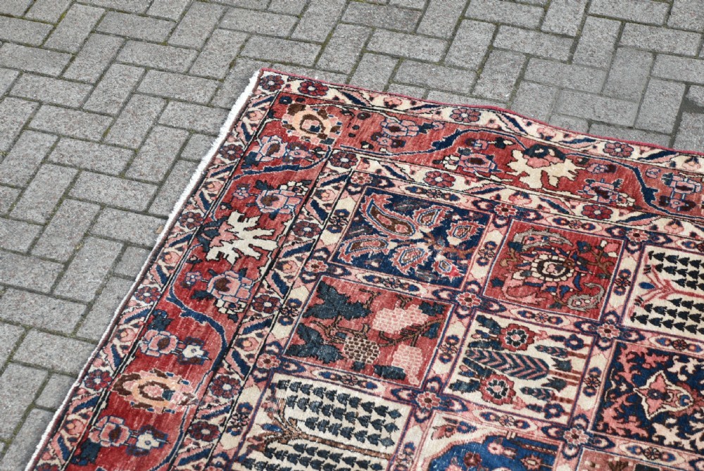 A hand-knotted Persian wool rug featuring a grid panel design with tree and floral motifs enclosed by a detailed terracotta border. View IV