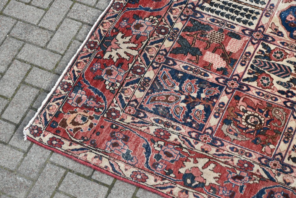 A hand-knotted Persian wool rug featuring a grid panel design with tree and floral motifs enclosed by a detailed terracotta border. View V