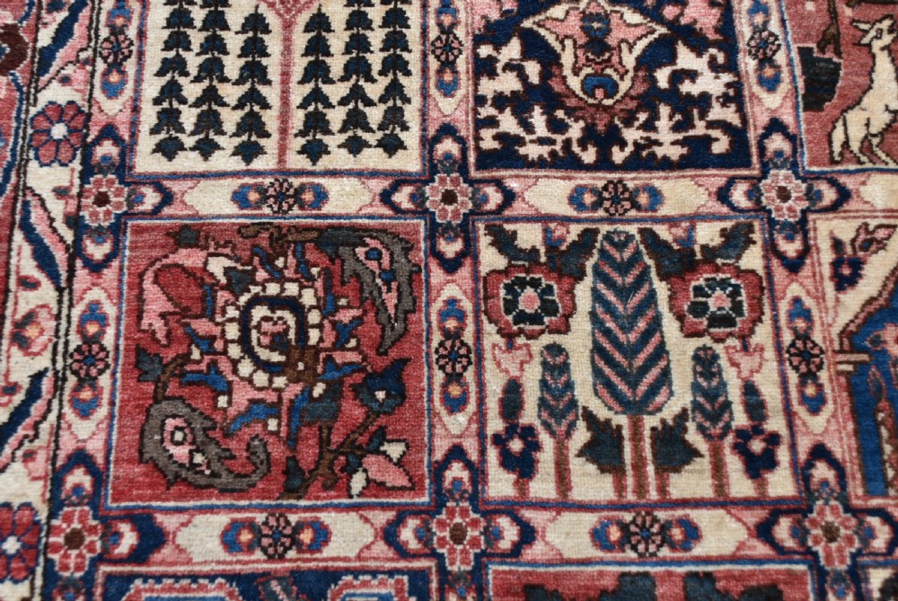 A hand-knotted Persian wool rug featuring a grid panel design with tree and floral motifs enclosed by a detailed terracotta border. View VIII