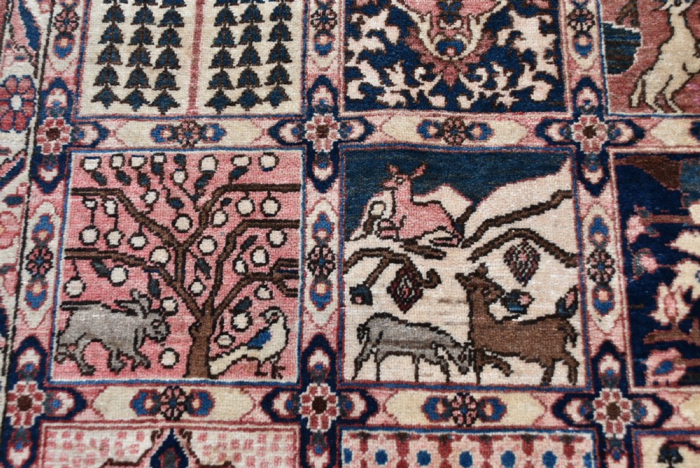 A hand-knotted Persian wool rug featuring a grid panel design with tree and floral motifs enclosed by a detailed terracotta border. View IX