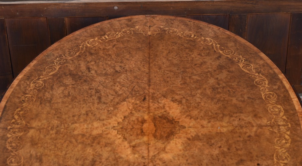 A Victorian oval burr walnut snap-top table featuring detailed floral marquetry inlay and a carved pedestal base displayed upright. View XIV