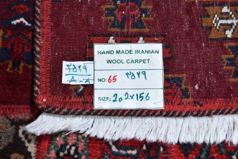 A rectangular hand-stitched Persian patchwork rug featuring geometric and floral panels in deep red, navy blue, and cream with white fringed edges. View IX