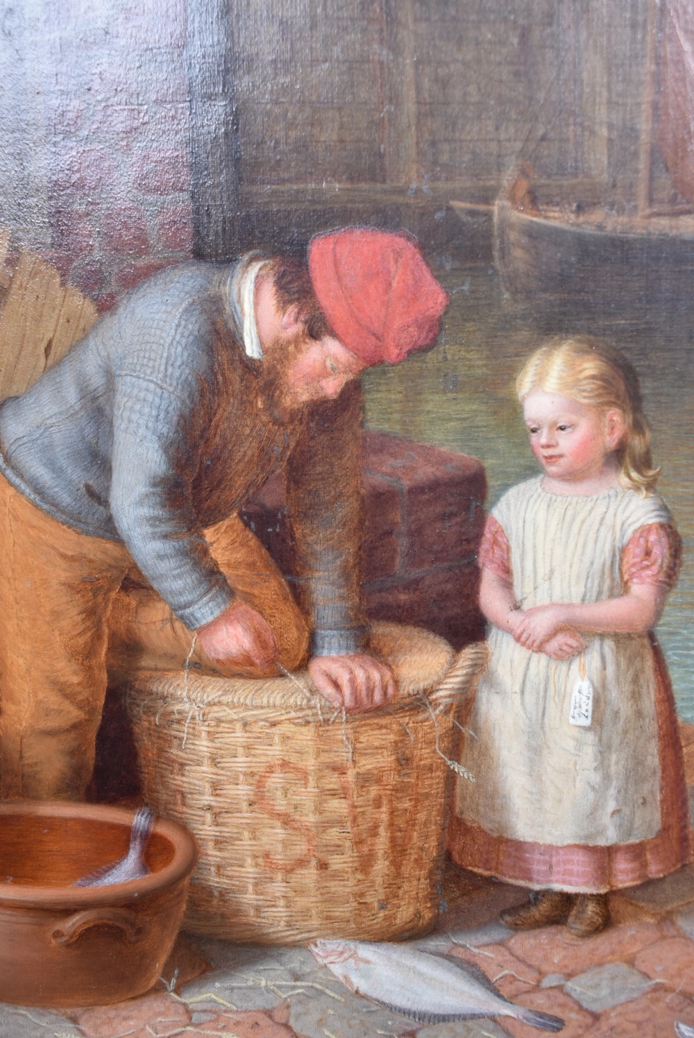 A Victorian oil painting on wood panel depicting a fisherman packing a wicker basket alongside a young girl, set within an ornate gilded frame. View X