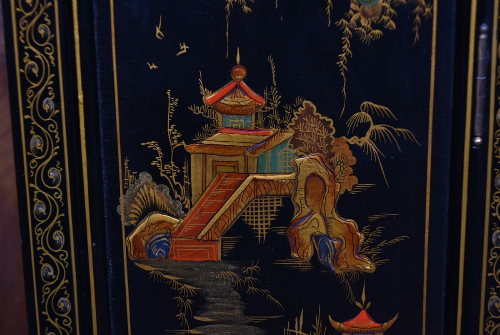 A slim black lacquered grandmother clock featuring hand-painted gilt chinoiserie landscape decoration, an arched hood, and a Roman numeral dial. View VI