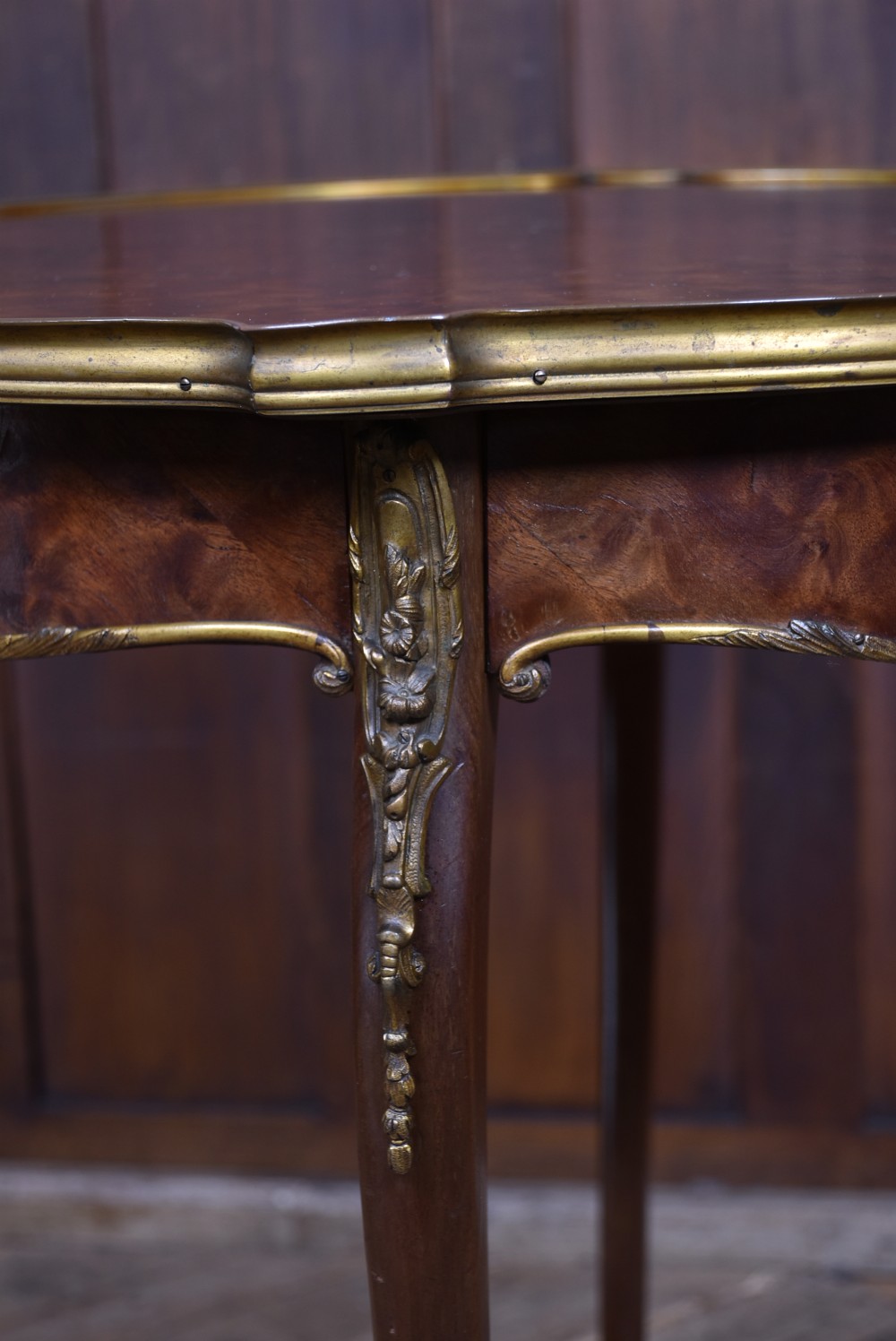 A French Louis XV style circular wooden occasional table featuring a veneer top, brass moulding, a lower shelf, and slim cabriole legs with metal mounts. View IX