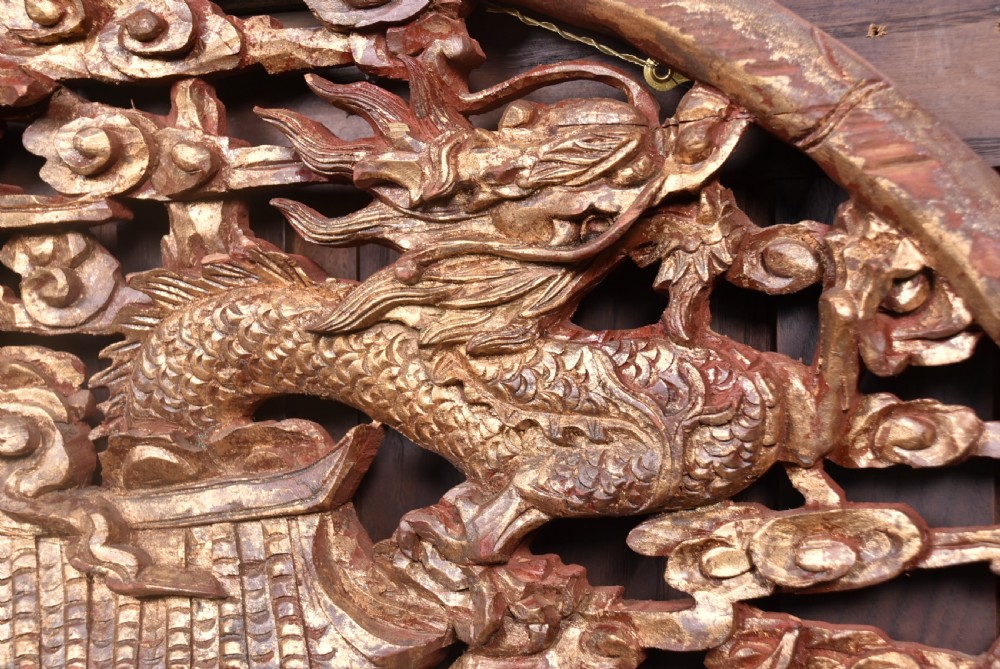 A circular 19th-century Chinese carved wooden wall plaque featuring gilded relief carvings of a dragon, carp, and pagodas. View II