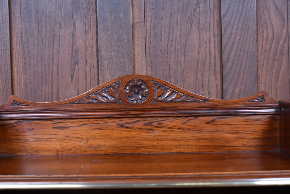 An Edwardian rosewood waterfall bookcase featuring four open graduated shelves with brass front rails and a carved rosette pediment. View V