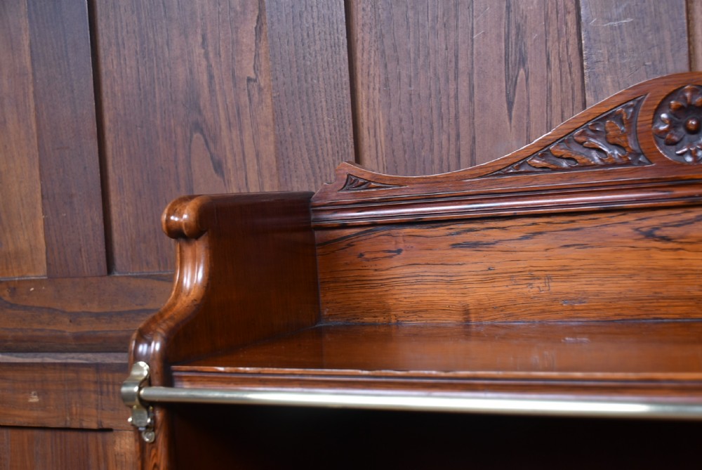 An Edwardian rosewood waterfall bookcase featuring four open graduated shelves with brass front rails and a carved rosette pediment. View VIII