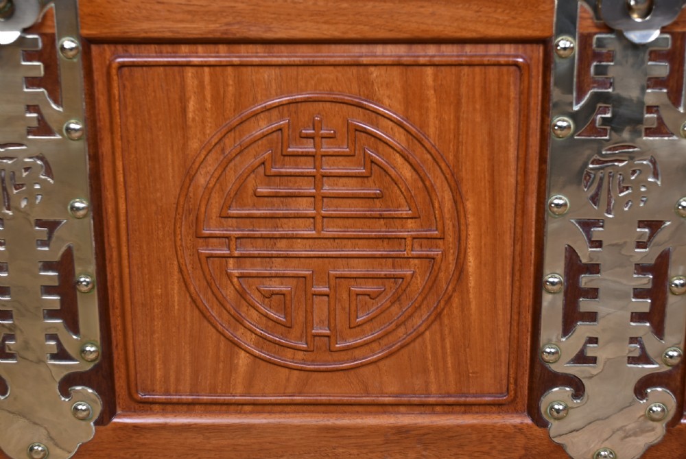 A rectangular reddish brown timber blanket box featuring carved Chinese character panels and polished brass corner fittings and straps. View VII