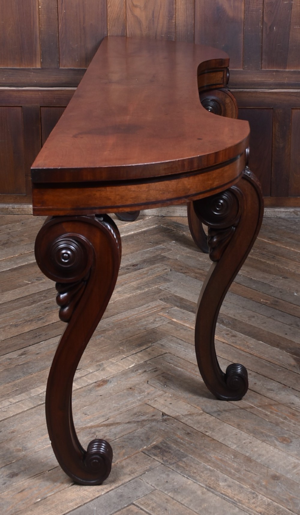 A 19th-century mahogany console table featuring a shaped top, inlaid frieze, and four carved scroll legs. View VI