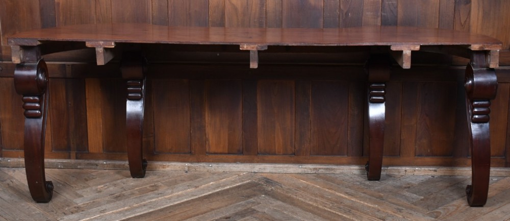 A 19th-century mahogany console table featuring a shaped top, inlaid frieze, and four carved scroll legs. View VII