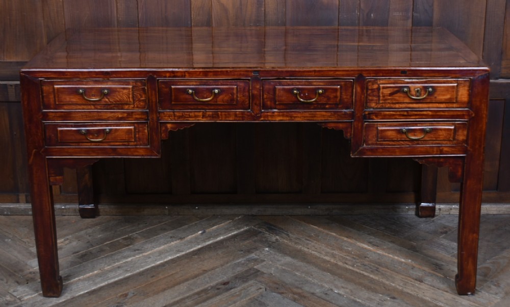 A traditional Chinese warm brown hardwood partners desk featuring six front drawers with brass drop handles and square legs.