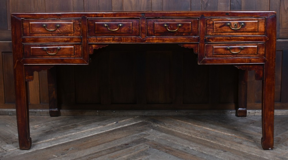 A traditional Chinese warm brown hardwood partners desk featuring six front drawers with brass drop handles and square legs. View II