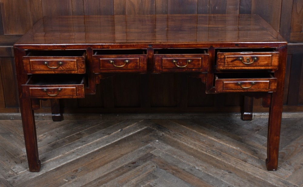 A traditional Chinese warm brown hardwood partners desk featuring six front drawers with brass drop handles and square legs. View VI