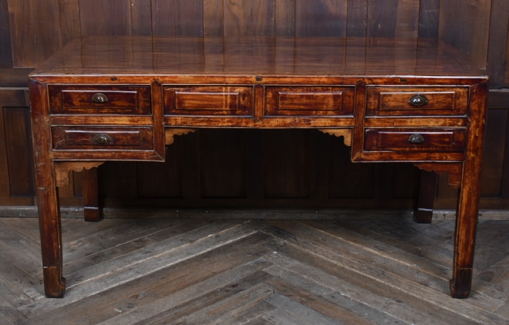 A traditional Chinese warm brown hardwood partners desk featuring six front drawers with brass drop handles and square legs. View XI