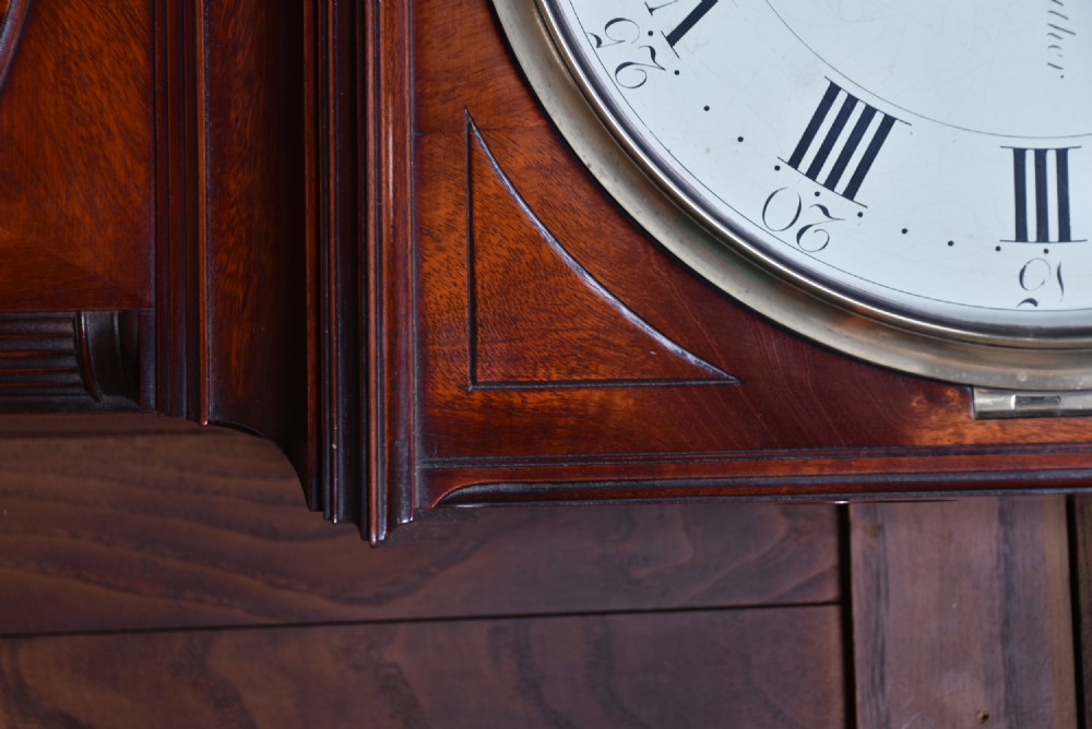 An antique Scottish flame mahogany longcase clock featuring a carved swan-neck pediment with brass finials, a rounded dial, and a veneered trunk door. View XIII