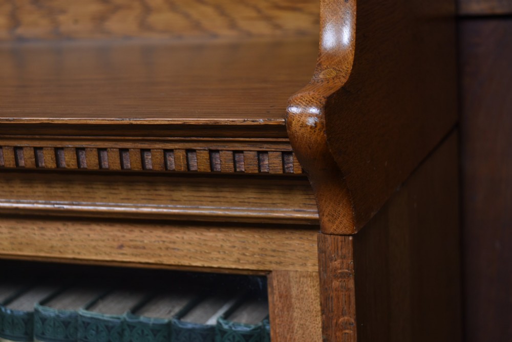 An Edwardian golden oak six-section bookcase featuring double columns of glass-fronted lifting doors and brass hardware. View II