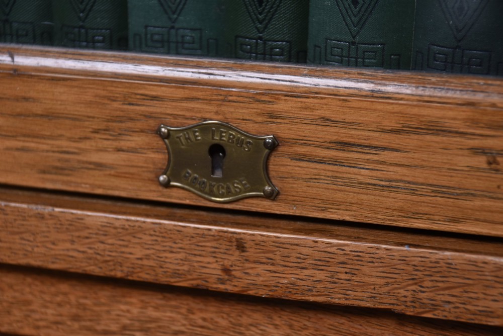 An Edwardian golden oak six-section bookcase featuring double columns of glass-fronted lifting doors and brass hardware. View III