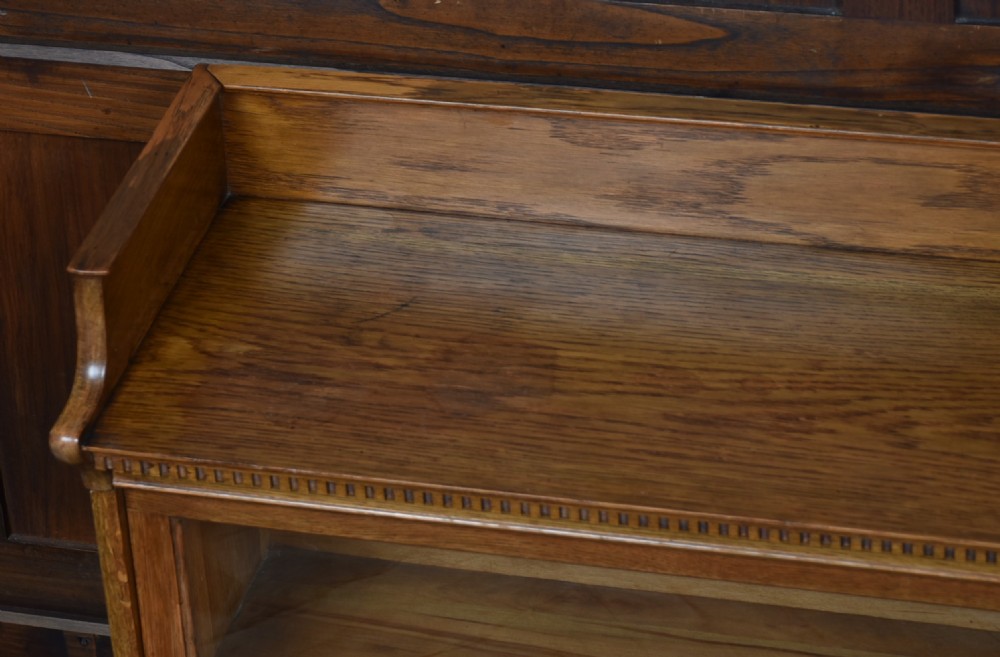 An Edwardian golden oak six-section bookcase featuring double columns of glass-fronted lifting doors and brass hardware. View VIII