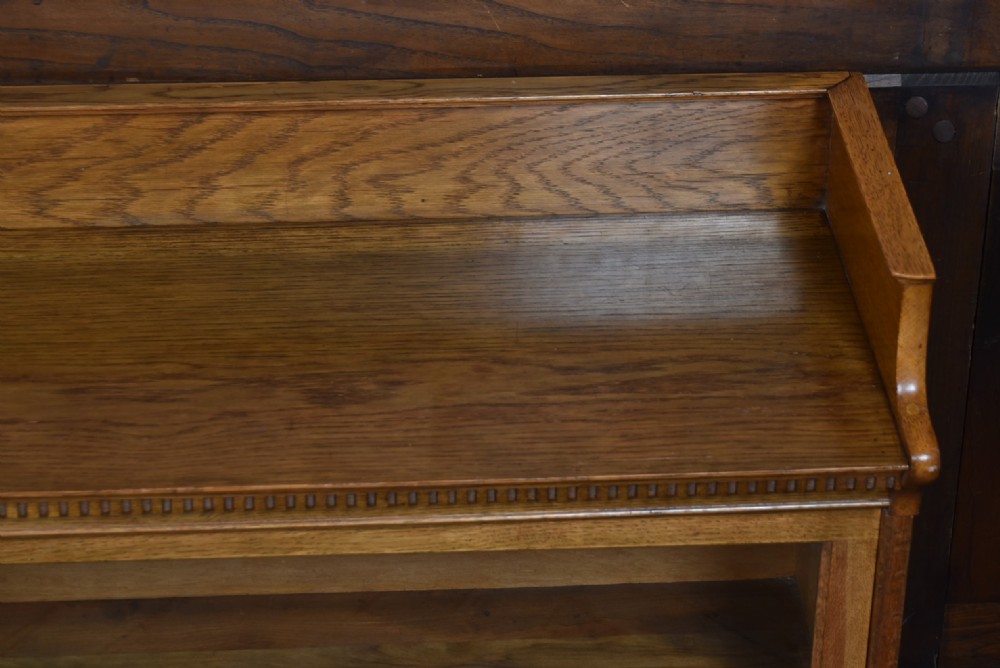 An Edwardian golden oak six-section bookcase featuring double columns of glass-fronted lifting doors and brass hardware. View IX