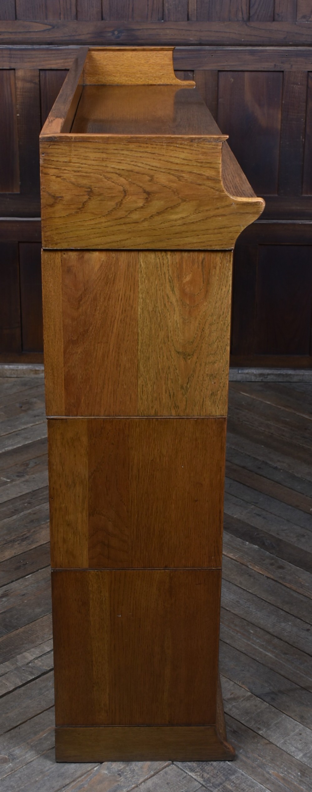 An Edwardian golden oak six-section bookcase featuring double columns of glass-fronted lifting doors and brass hardware. View XIII