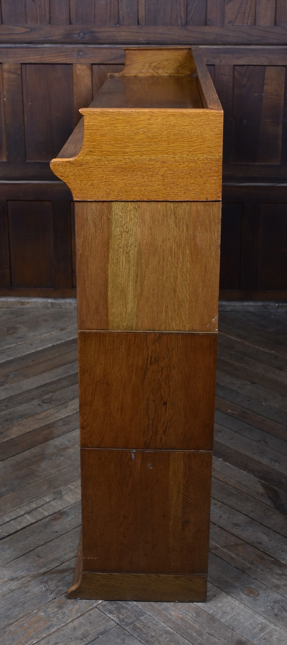 An Edwardian golden oak six-section bookcase featuring double columns of glass-fronted lifting doors and brass hardware. View XIV
