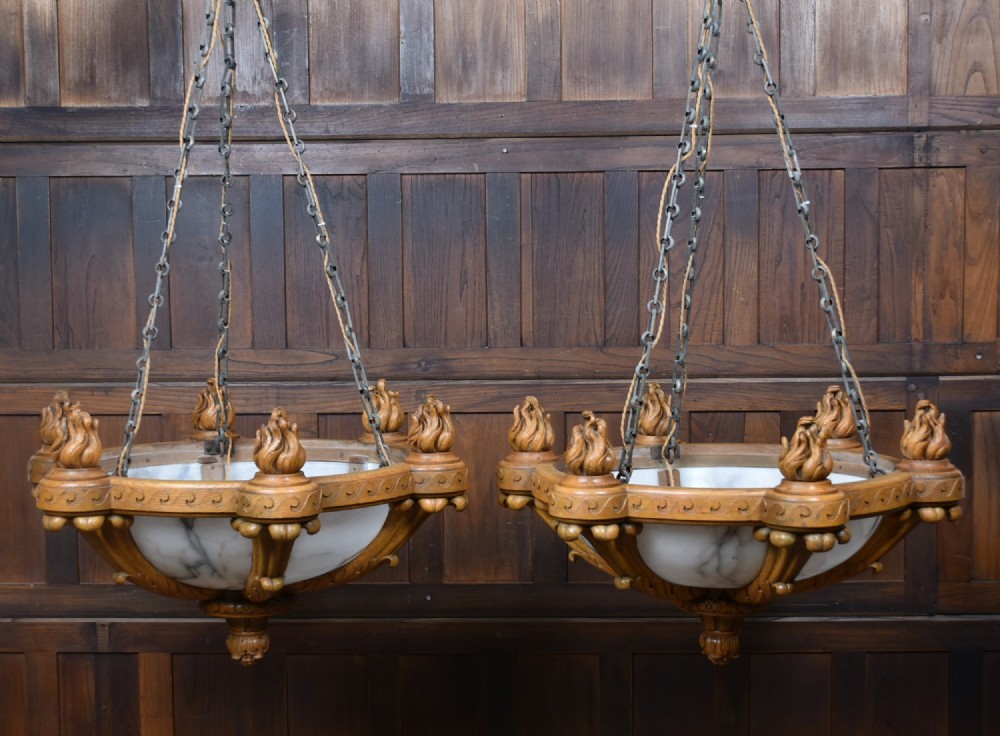 A pair of Art Deco ceiling lights featuring translucent veined alabaster bowls encased in carved wooden rims with flame finials and metal chains. View II