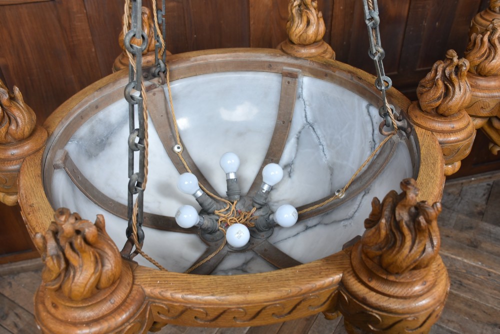 A pair of Art Deco ceiling lights featuring translucent veined alabaster bowls encased in carved wooden rims with flame finials and metal chains. View IV
