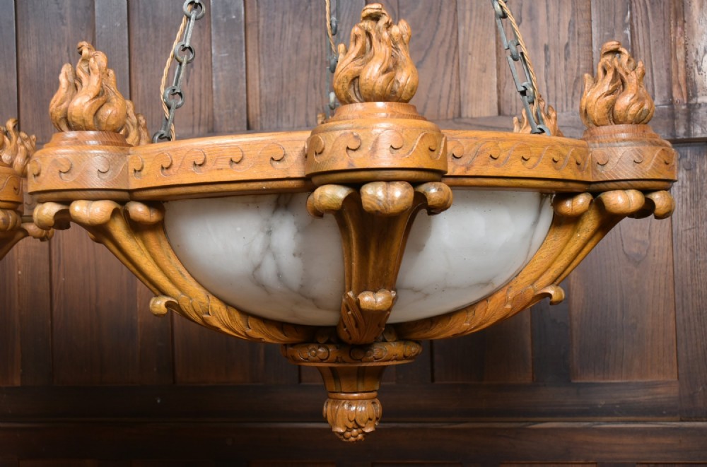A pair of Art Deco ceiling lights featuring translucent veined alabaster bowls encased in carved wooden rims with flame finials and metal chains. View VI