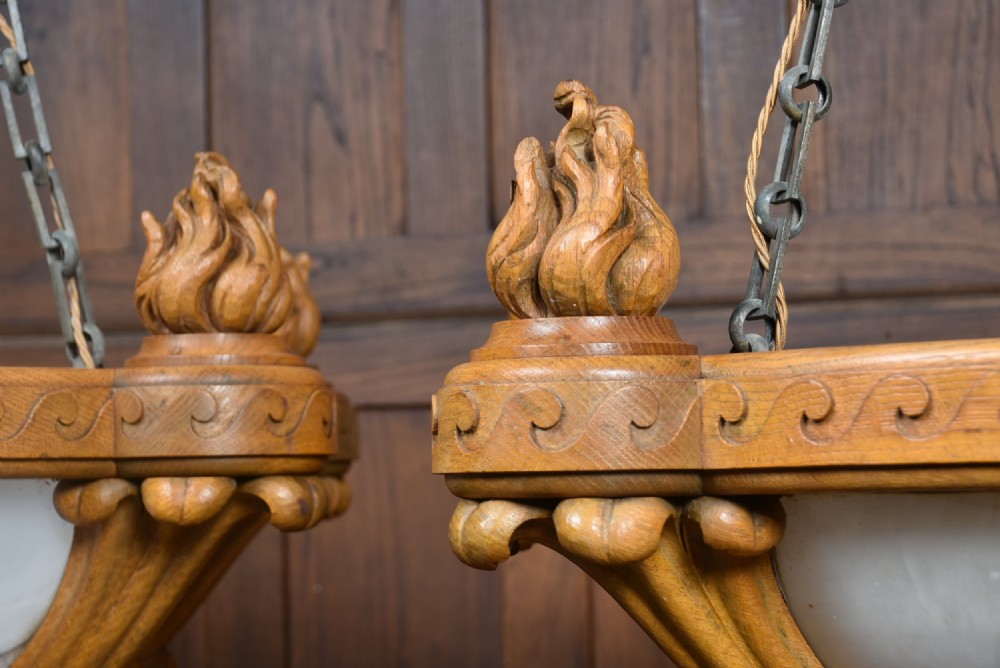 A pair of Art Deco ceiling lights featuring translucent veined alabaster bowls encased in carved wooden rims with flame finials and metal chains. View VII