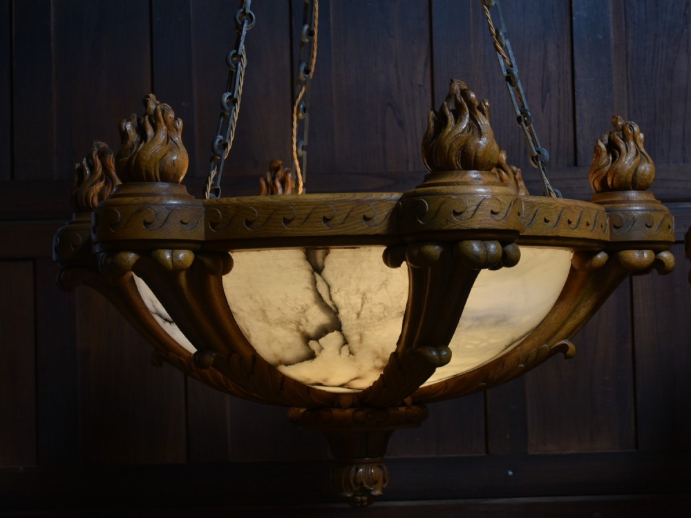 A pair of Art Deco ceiling lights featuring translucent veined alabaster bowls encased in carved wooden rims with flame finials and metal chains. View VIII