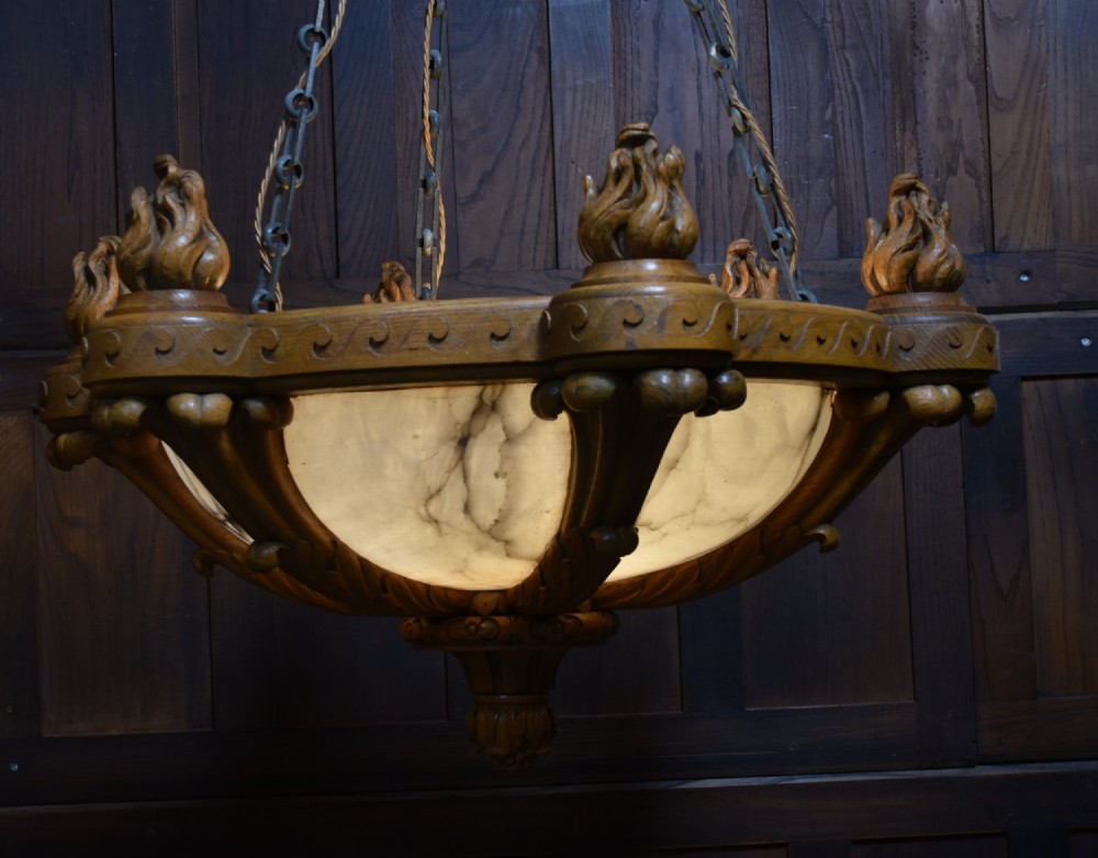 A pair of Art Deco ceiling lights featuring translucent veined alabaster bowls encased in carved wooden rims with flame finials and metal chains. View IX