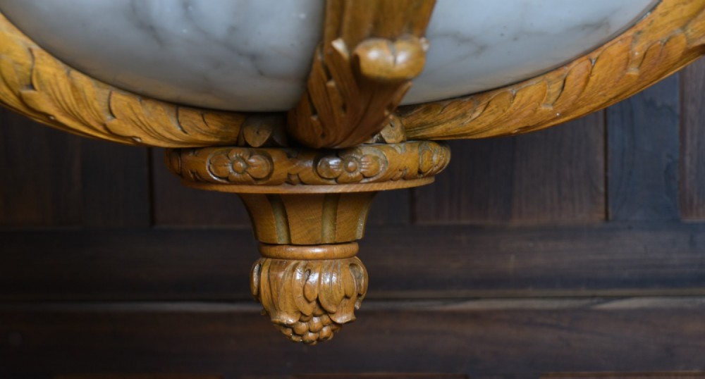 A pair of Art Deco ceiling lights featuring translucent veined alabaster bowls encased in carved wooden rims with flame finials and metal chains. View XI