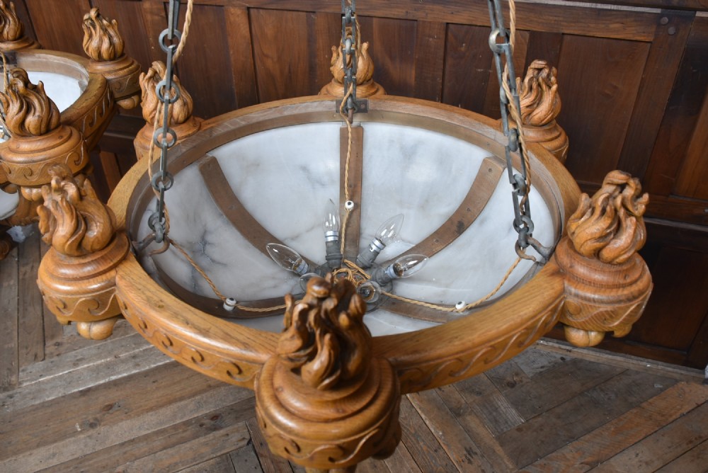 A pair of Art Deco ceiling lights featuring translucent veined alabaster bowls encased in carved wooden rims with flame finials and metal chains. View XII