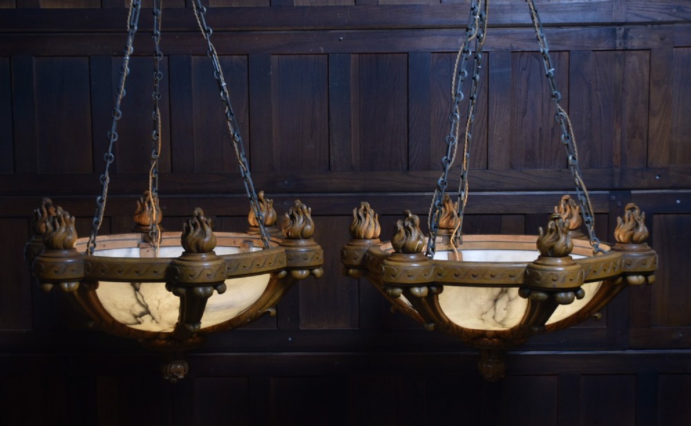 A pair of Art Deco ceiling lights featuring translucent veined alabaster bowls encased in carved wooden rims with flame finials and metal chains. View XIII