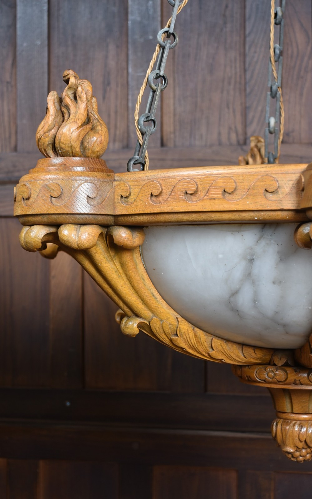 A pair of Art Deco ceiling lights featuring translucent veined alabaster bowls encased in carved wooden rims with flame finials and metal chains. View XIV