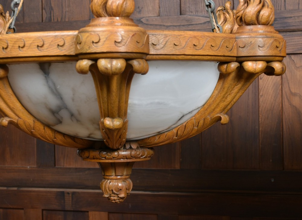 A pair of Art Deco ceiling lights featuring translucent veined alabaster bowls encased in carved wooden rims with flame finials and metal chains. View XV