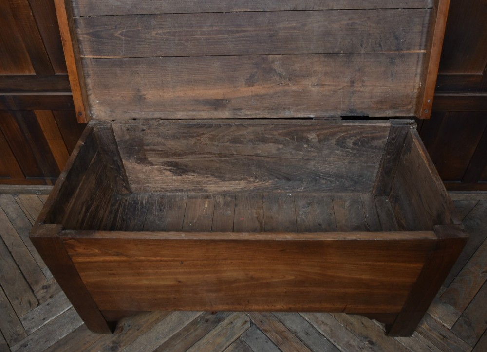 An antique French cherrywood blanket box with a hinged rectangular lid, natural wood grain, and shaped corner apron. View V