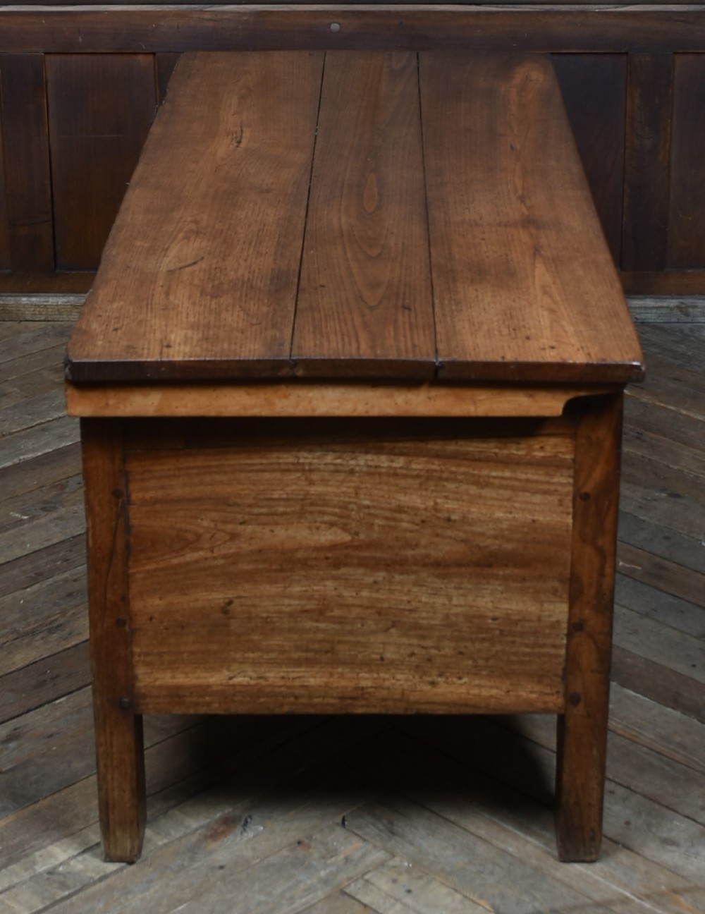 An antique French cherrywood blanket box with a hinged rectangular lid, natural wood grain, and shaped corner apron. View VI