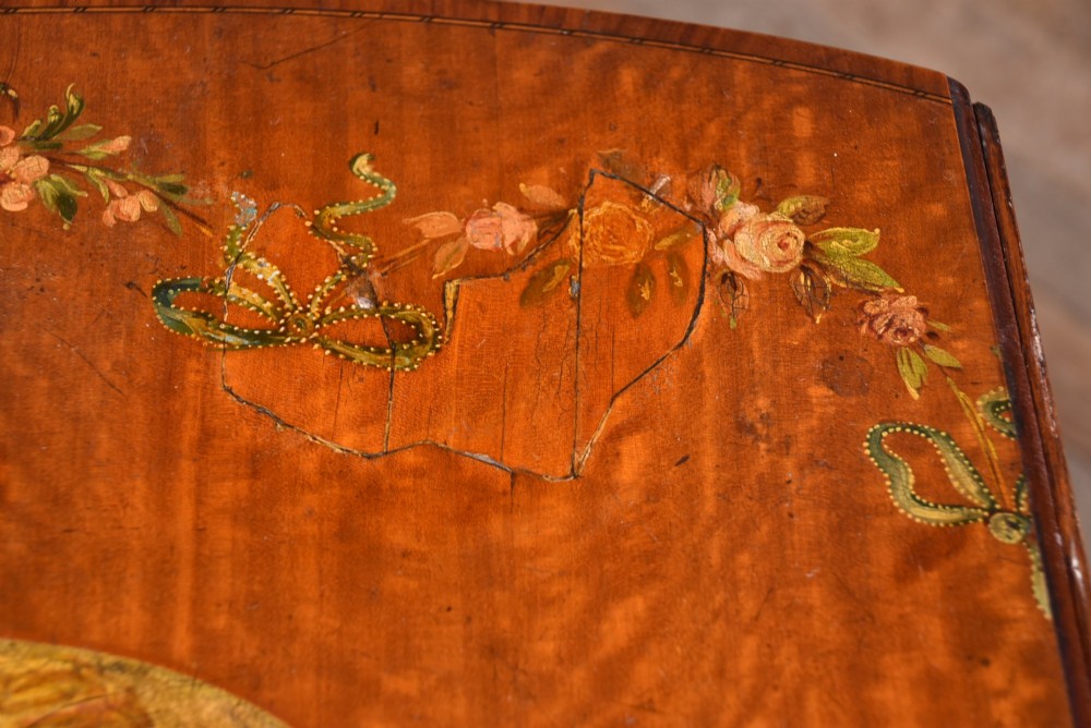 An Edwardian Neoclassical drop-leaf table featuring hand-painted floral swags, a central figural medallion, fluted turned legs, and an X-stretcher on castors. View VIII