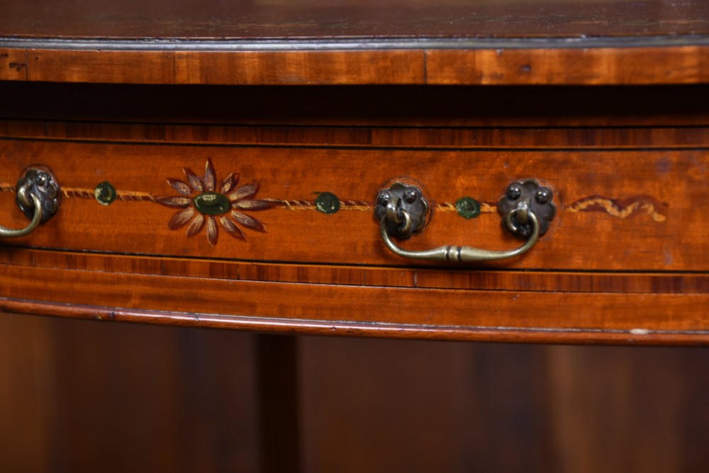 An Edwardian Neoclassical drop-leaf table featuring hand-painted floral swags, a central figural medallion, fluted turned legs, and an X-stretcher on castors. View XII
