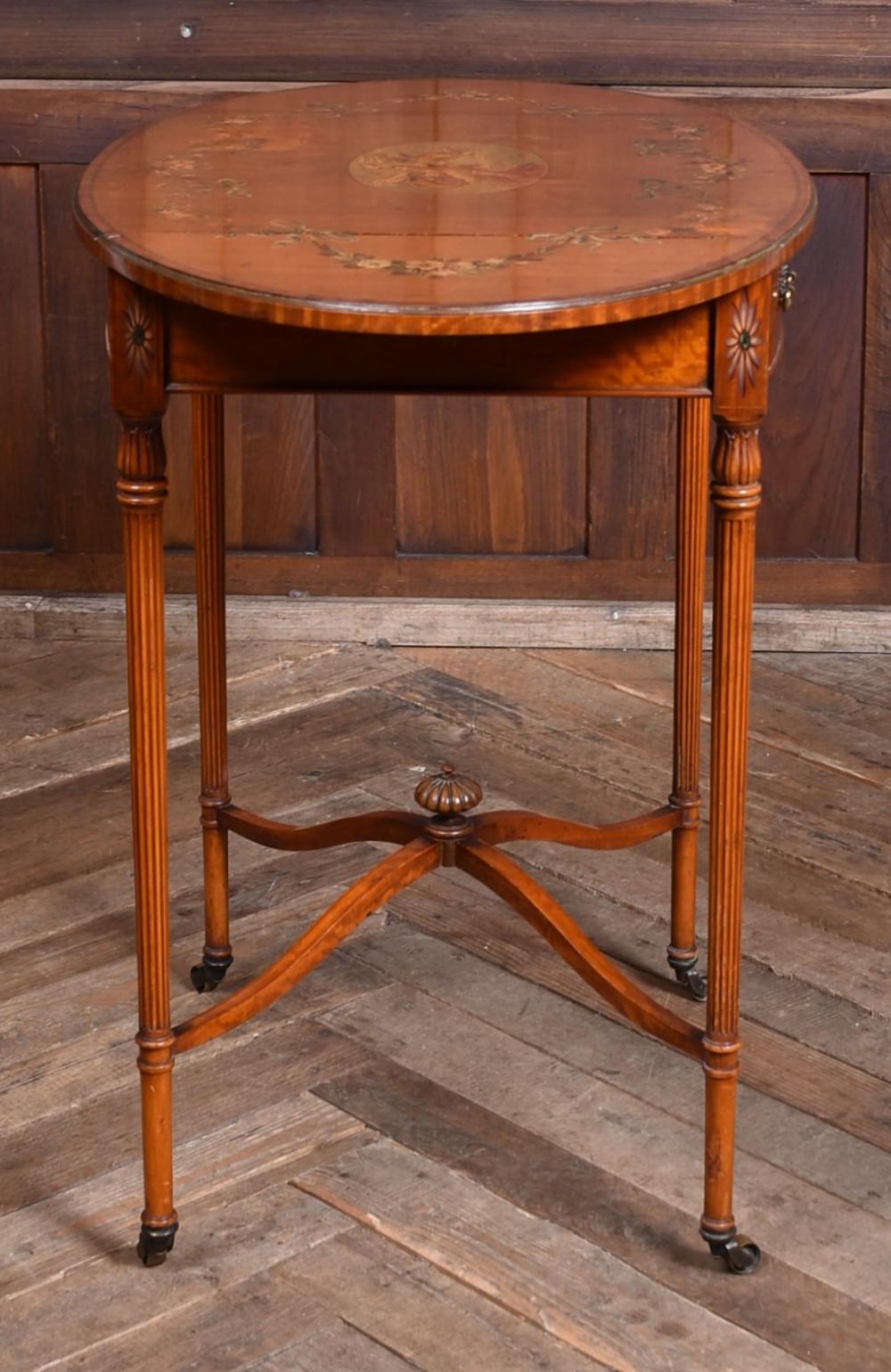 An Edwardian Neoclassical drop-leaf table featuring hand-painted floral swags, a central figural medallion, fluted turned legs, and an X-stretcher on castors. View XIII