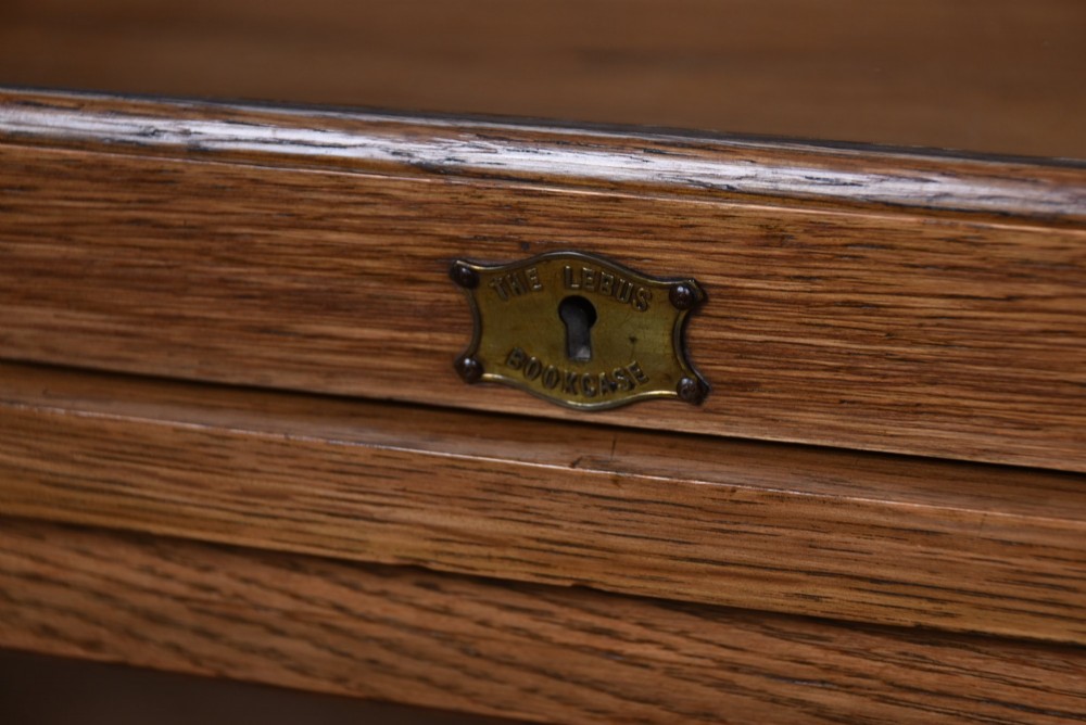 A three-tier Edwardian oak sectional bookcase featuring glass up-and-over doors with small brass knobs and a galleried top. View II